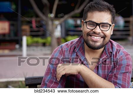 Smiling Hispanic man with beard sitting on bench View Large Photo Image Stock Image - Smiling Hispanic man with beard sitting on bench. Fotosearch