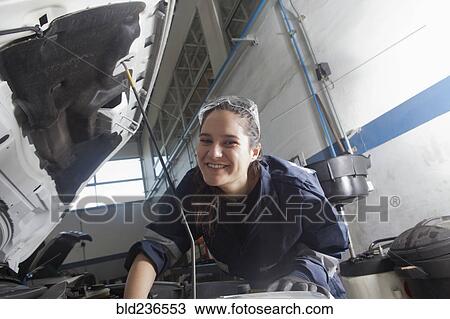 Stock Image - Smiling Hispanic mechanic repairing car engine. Fotosearch