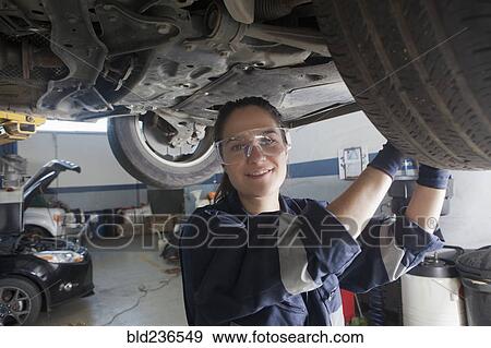 Stock Photo - Smiling Hispanic mechanic repairing car. Fotosearch