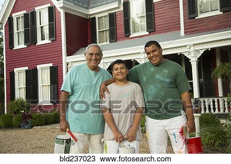 Stock Image - Smiling Hispanic men and boy posing with paint cans. Fotosearch