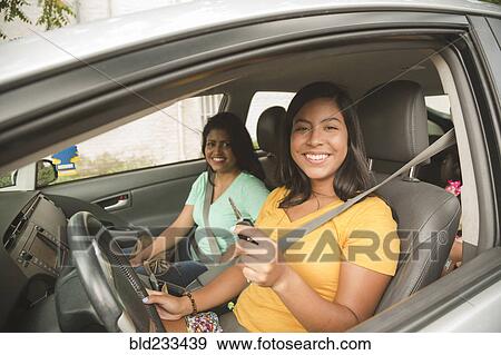 Stock Photo - Smiling Hispanic mother and daughter posing in car. Fotosearch