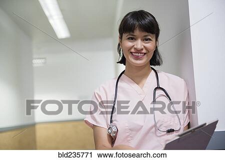 Smiling Hispanic nurse holding clipboard View Large Photo Image Stock Image - Smiling Hispanic nurse holding clipboard. Fotosearch