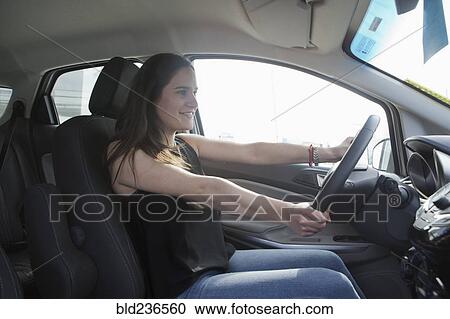 Stock Image - Smiling Hispanic woman driving car. Fotosearch