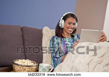 Smiling Hispanic woman sitting on sofa with digital tablet View Large Photo Image Stock Photo - Smiling Hispanic woman sitting on sofa with digital tablet. Fotosearch