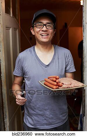 Smiling Japanese man holding plate of raw meat in doorway View Large Photo Image Stock Image - Smiling Japanese man holding plate of raw meat in doorway. Fotosearch
