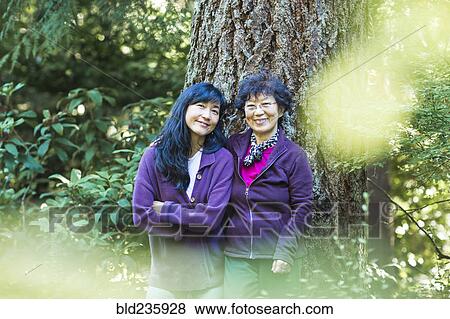 Smiling Japanese mother and daughter posing near tree trunk View Large Photo Image Stock Photo - Smiling Japanese mother and daughter posing near tree trunk. Fotosearch
