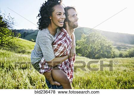 Smiling Man carrying girlfriend piggyback on hill View Large Photo Image Stock Photo - Smiling Man carrying girlfriend piggyback on hill. Fotosearch