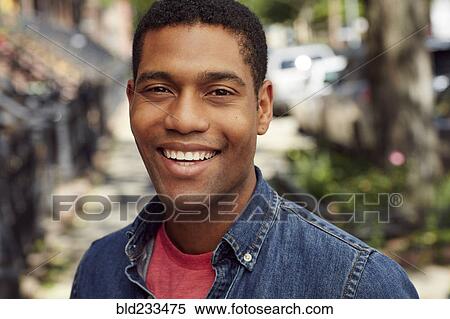 Stock Photography - Smiling man posing on city sidewalk. Fotosearch