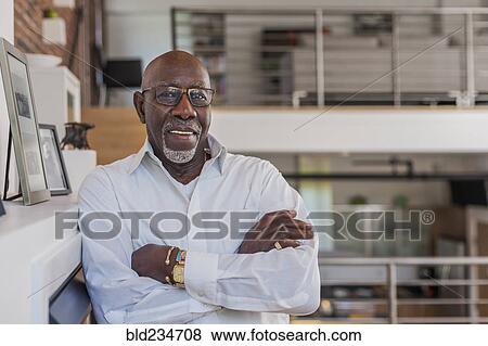 Smiling man with arms crossed leaning on mantle View Large Photo Image Stock Photo - Smiling man with arms crossed leaning on mantle. Fotosearch