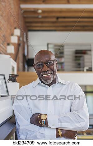 Smiling man with arms crossed leaning on mantle View Large Photo Image Stock Photo - Smiling man with arms crossed leaning on mantle. Fotosearch