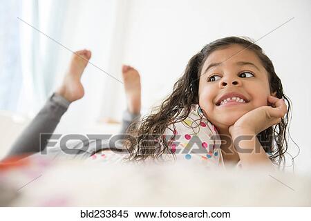 Smiling Mixed Race girl laying on bed View Large Photo Image Stock Photography - Smiling Mixed Race girl laying on bed. Fotosearch