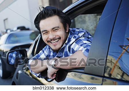 Stock Photo - Smiling mixed race man in compact car. Fotosearch