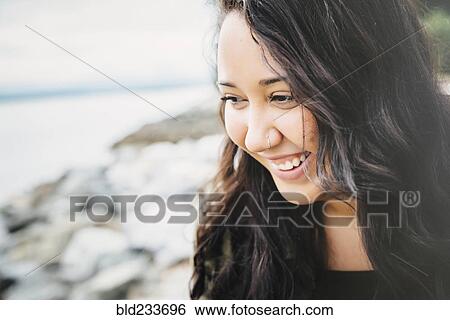 Stock Photograph - Smiling Mixed Race woman at ocean. Fotosearch