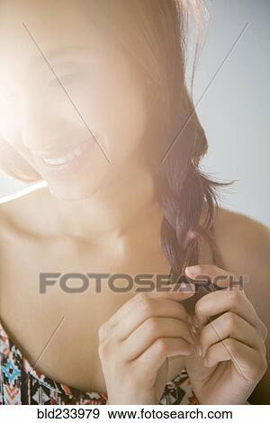 Stock Photo - Smiling Mixed Race woman braiding hair. Fotosearch