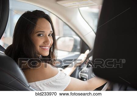 Stock Image - Smiling Mixed Race woman driving car. Fotosearch
