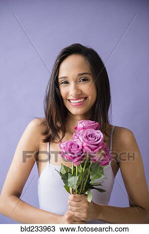 Stock Image - Smiling Mixed Race woman holding bouquet of roses. Fotosearch