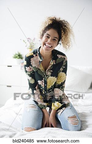 Smiling Mixed Race woman kneeling on bed View Large Photo Image Stock Photography - Smiling Mixed Race woman kneeling on bed. Fotosearch