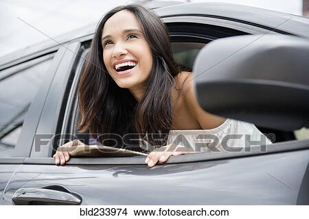 Picture - Smiling Mixed Race woman leaning out car window. Fotosearch