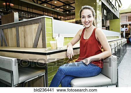 Stock Image - Smiling Mixed Race woman posing in food court. Fotosearch