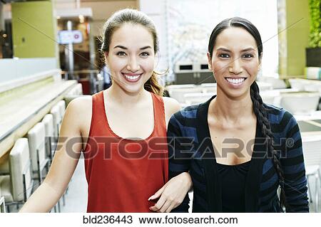 Stock Image - Smiling Mixed Race women posing in food court. Fotosearch
