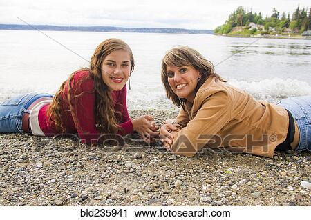 Smiling mother and daughter laying on rocky beach View Large Photo Image Stock Image - Smiling mother and daughter laying on rocky beach. Fotosearch