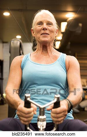 Smiling older woman working out in gymnasium View Large Photo Image Stock Image - Smiling older woman working out in gymnasium. Fotosearch
