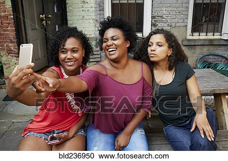 Smiling woman posing for cell phone selfie View Large Photo Image Stock Image - Smiling woman posing for cell phone selfie. Fotosearch
