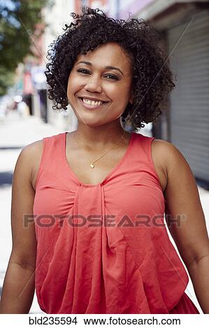 Picture - Smiling woman posing on city sidewalk. Fotosearch