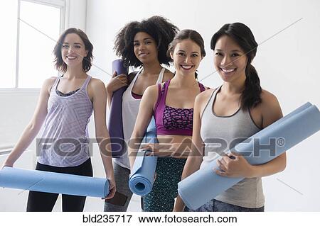 Stock Photo - Smiling women holding rolled up exercise mats. Fotosearch