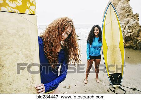 Smiling women holding surfboards at beach View Large Photo Image Stock Photo - Smiling women holding surfboards at beach. Fotosearch