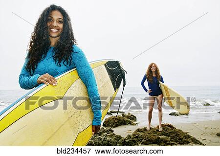 Smiling women holding surfboards at beach View Large Photo Image Stock Photo - Smiling women holding surfboards at beach . Fotosearch