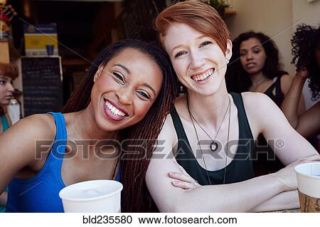 Stock Image - Smiling women in coffee shop. Fotosearch