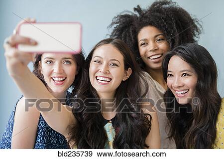 Smiling women posing for cell phone selfie View Large Photo Image Stock Photo - Smiling women posing for cell phone selfie. Fotosearch