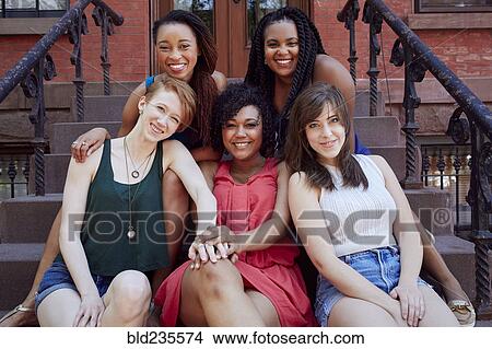Picture - Smiling women sitting on urban front stoop. Fotosearch