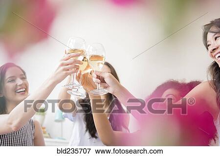 Smiling women toasting with white wine View Large Photo Image Stock Photo - Smiling women toasting with white wine. Fotosearch