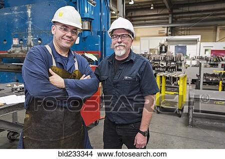 Picture - Smiling workers posing in factory. Fotosearch