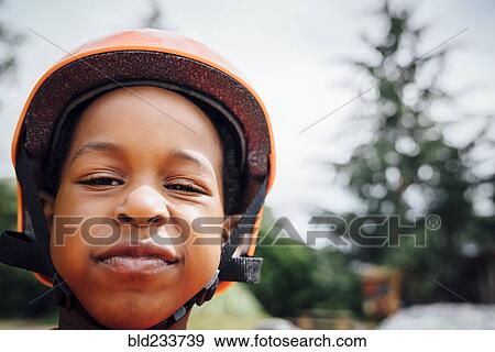 Stock Photo - Sneering Black boy wearing helmet. Fotosearch