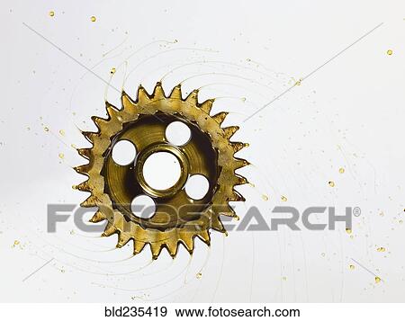 Stock Photo - Spinning gear spraying oil. Fotosearch