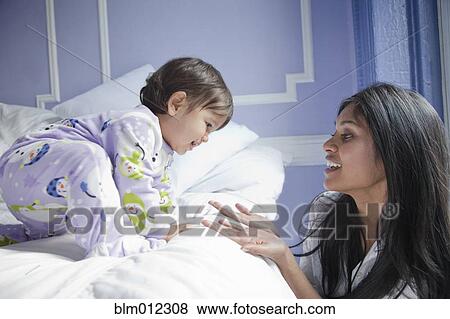 Stock Photo - Sri Lankan mother taking baby girl off bed. Fotosearch
