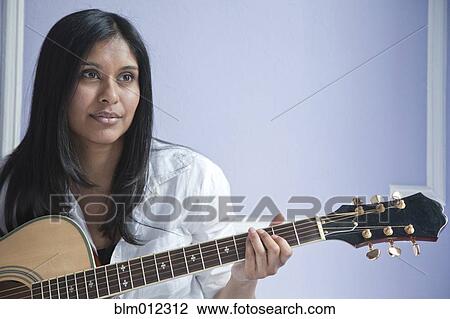 Stock Image - Sri Lankan woman playing guitar. Fotosearch