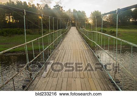 Sunbeams on wooden footbridge over river View Large Photo Image Stock Photograph - Sunbeams on wooden footbridge over river. Fotosearch