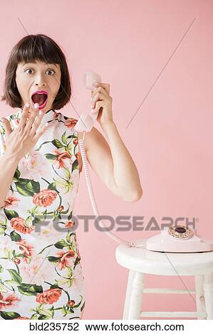 Surprised Hispanic woman wearing floral dress holding pink telephone View Large Photo Image Stock Image - Surprised Hispanic woman wearing floral dress holding pink telephone. Fotosearch
