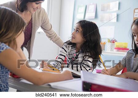 Teacher helping girls in classroom View Large Photo Image Stock Image - Teacher helping girls in classroom. Fotosearch