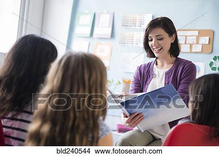 Picture - Teacher reading book to girls in classroom. Fotosearch