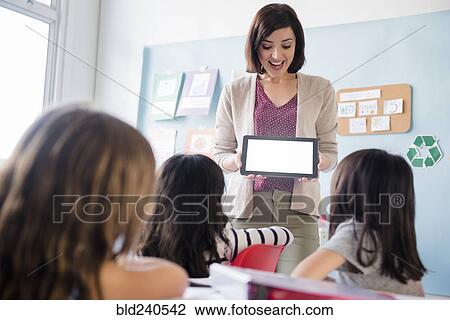 Teacher showing digital tablet to girls in classroom View Large Photo Image Stock Image - Teacher showing digital tablet to girls in classroom. Fotosearch