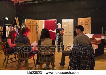 Stock Image - Teacher talking to students in theater class. Fotosearch