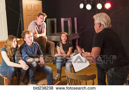 Stock Photo - Teacher talking to students in theater class. Fotosearch