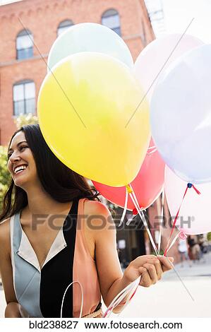 Stock Photo - Thai woman holding balloons in city. Fotosearch
