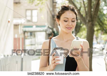 Thai woman holding coffee texting on cell phone in city View Large Photo Image Stock Image - Thai woman holding coffee texting on cell phone in city. Fotosearch