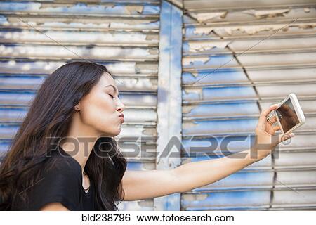 Thai woman puckering for cell phone selfie View Large Photo Image Stock Photograph - Thai woman puckering for cell phone selfie. Fotosearch